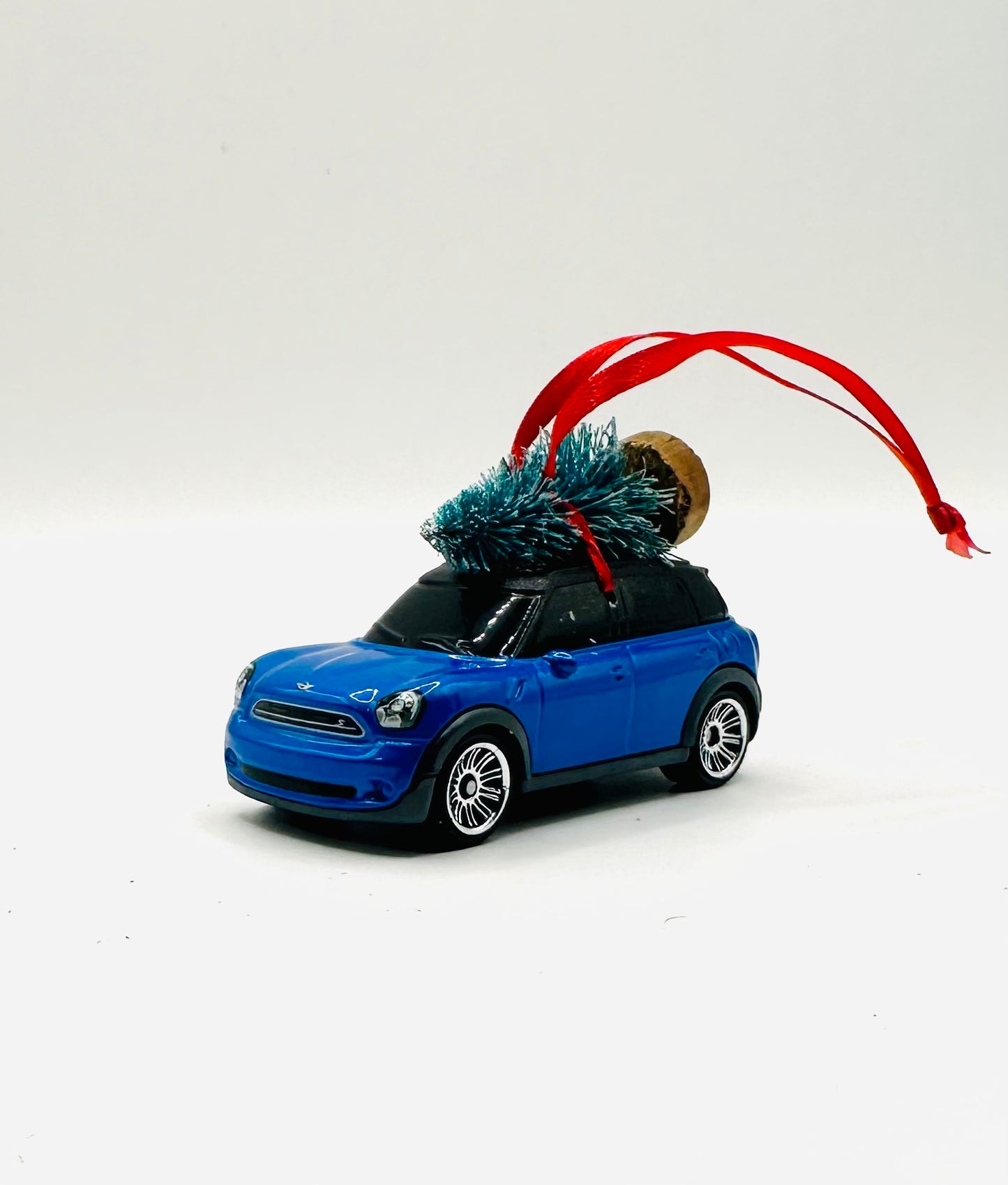 Blue mini car ornament with a Christmas tree on top against a white background