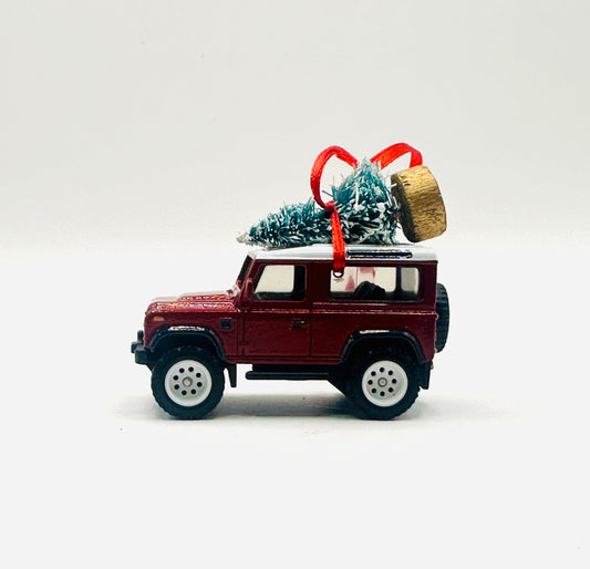 Model of a red SUV with a Christmas tree and gift on top against a white background