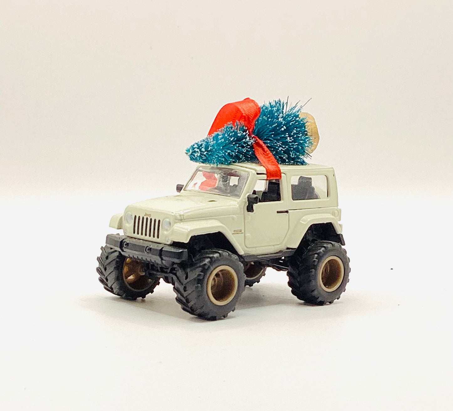 Toy jeep with a Christmas tree on top against a white background