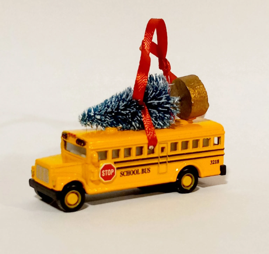 Yellow school bus ornament with a Christmas tree on top against a white background