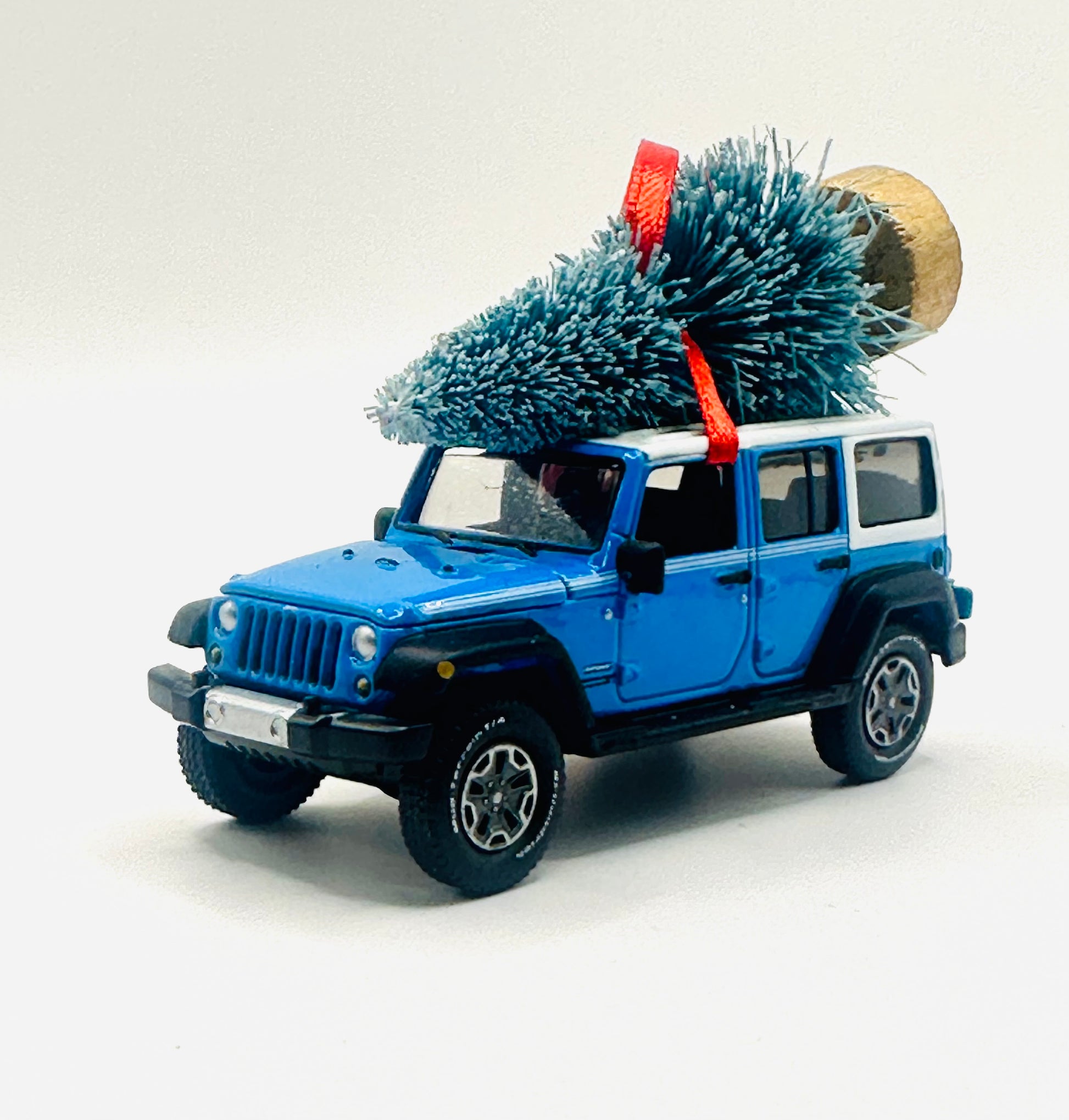 Classic Chief Blue Jeep Wrangler JK Unlimited ornament with festive Christmas tree and red ribbon - angle view