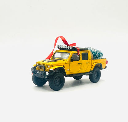 Lifted yellow Jeep Gladiator diecast ornament with roof rack, off-road lights, and Christmas tree in bed - side view