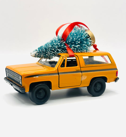 Vintage orange Chevy Blazer K5 ornament with two-tone paint, Christmas tree, and red ribbon - front angle view