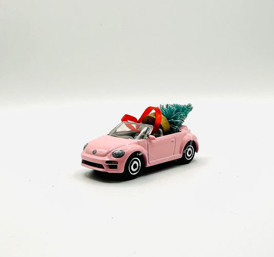 Pink convertible toy car with Christmas decorations on a white background