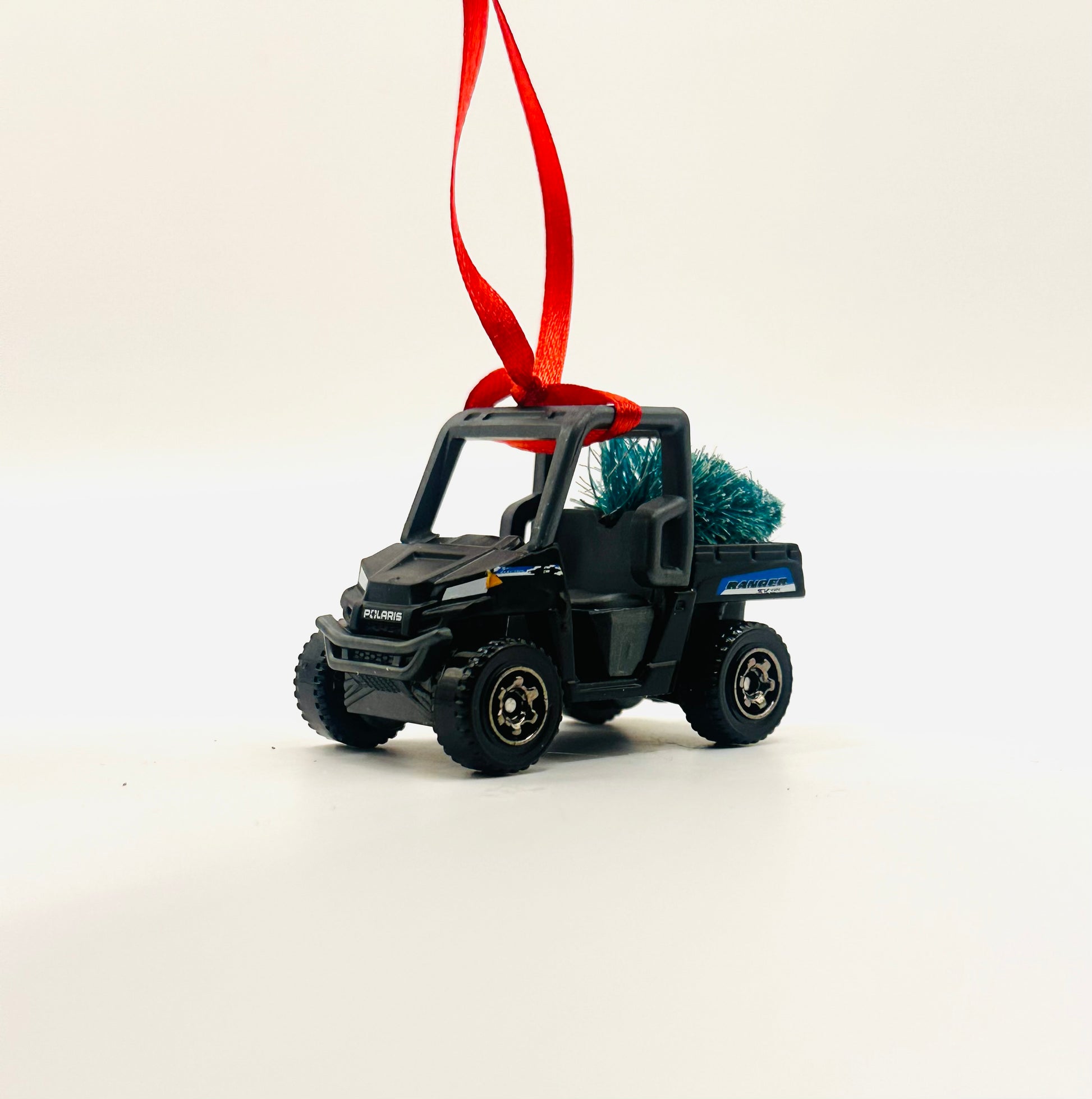 Toy UTV vehicle ornament with a small Christmas tree on a white background