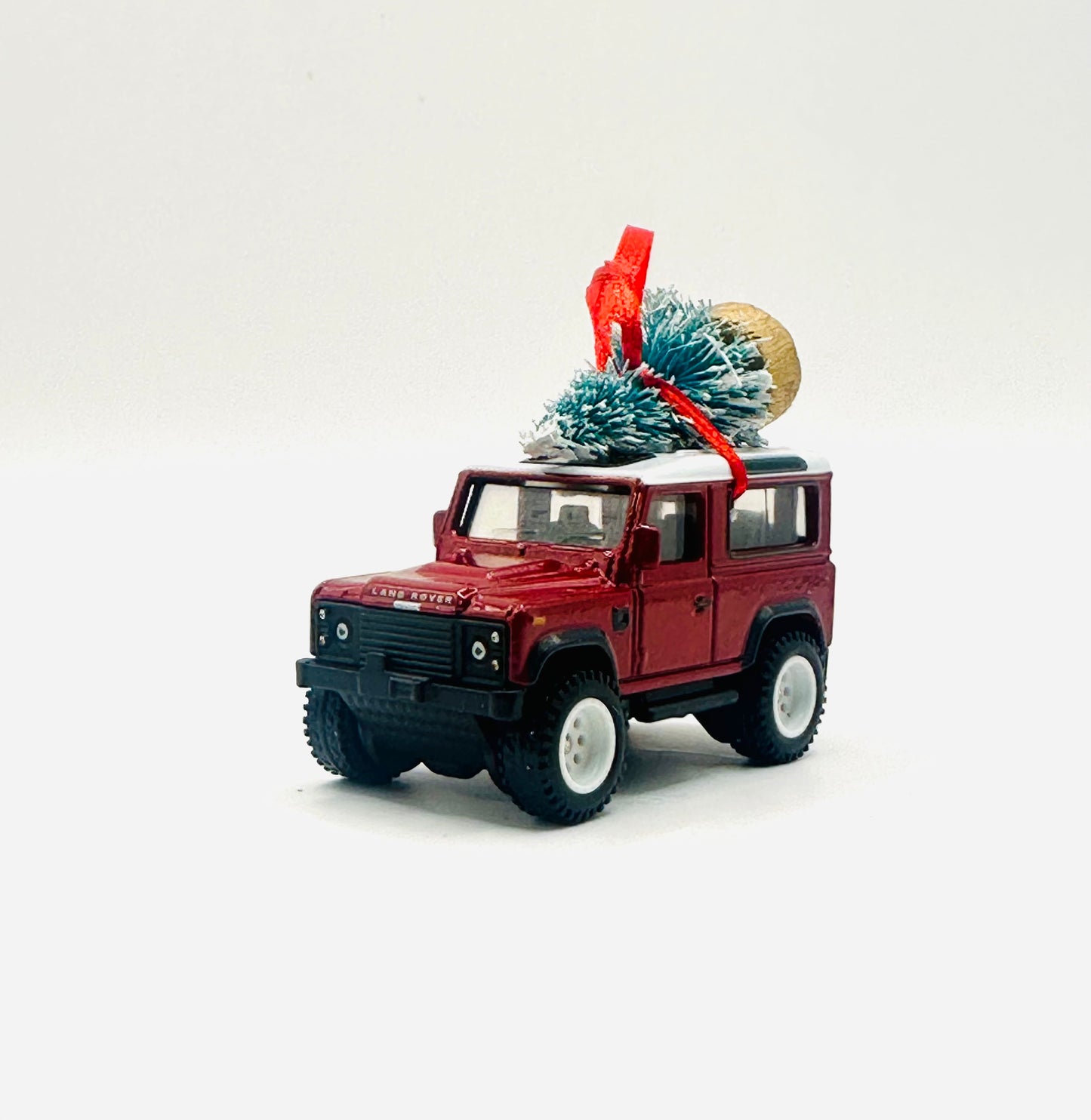 Model of a red Land Rover with a Christmas tree on a white background