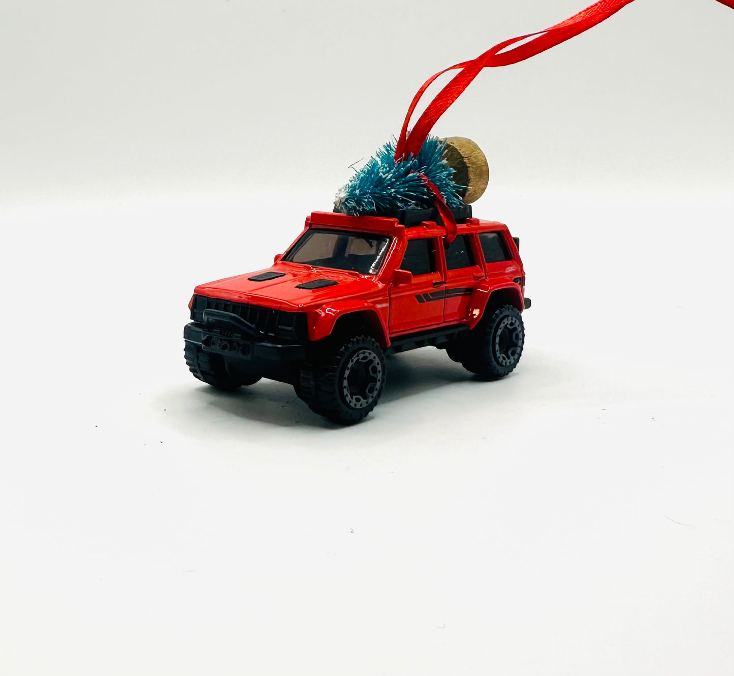 Red toy Jeep Cherokee with a Christmas tree on top against a white background