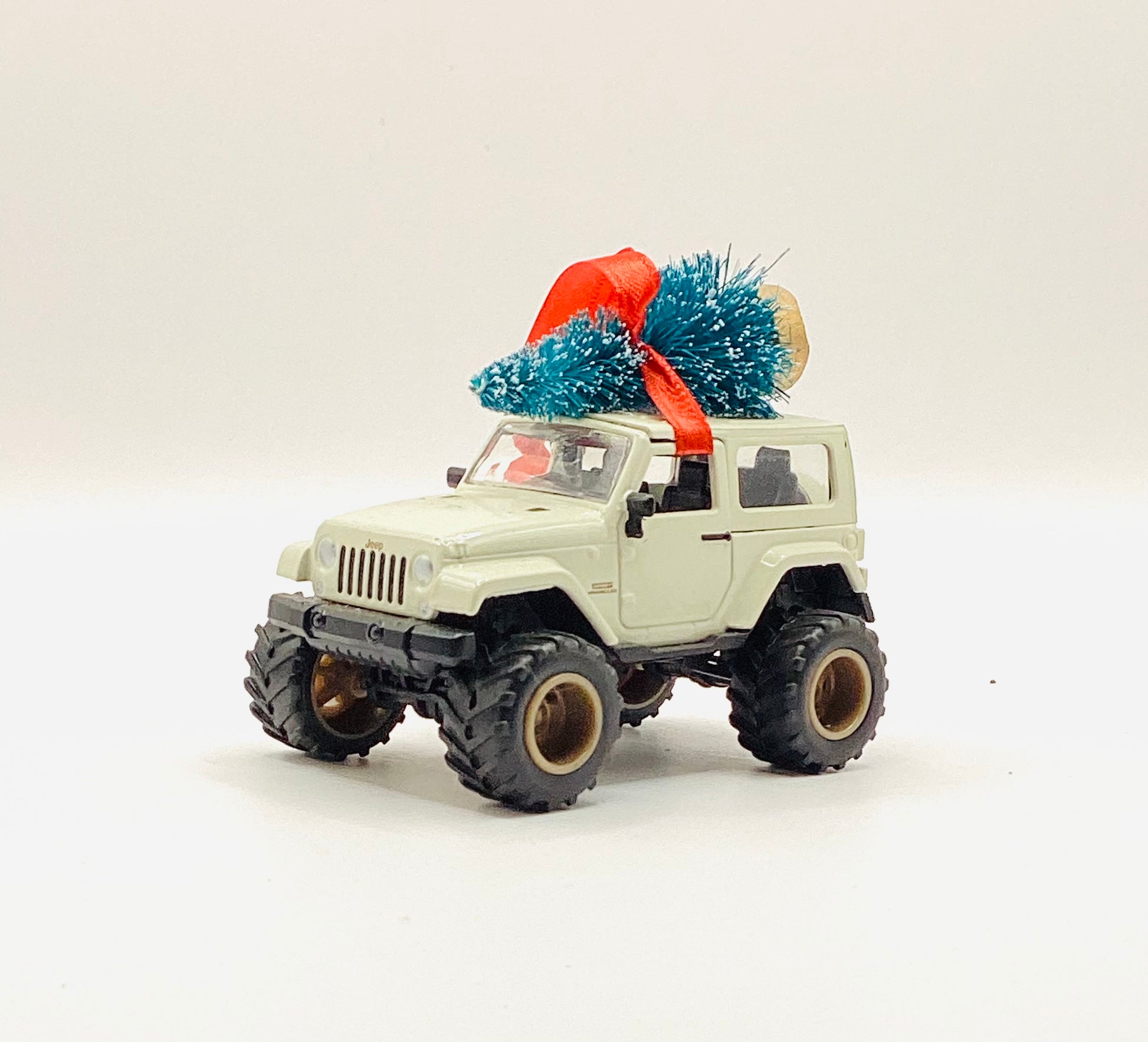 Toy jeep with a Christmas tree on top against a white background